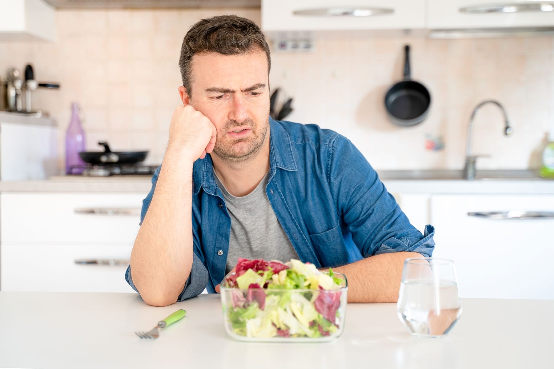 Man looks at salad with disgust, while dealing with eating disorder triggers